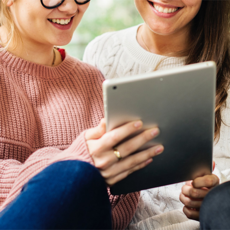 Closeup of two smiling women looking at a tablet